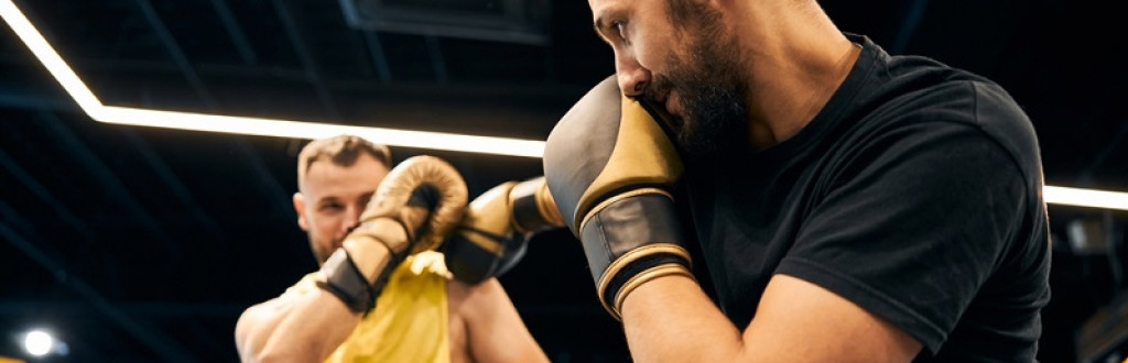 male boxer in a yellow shirt parrying his opponents punch