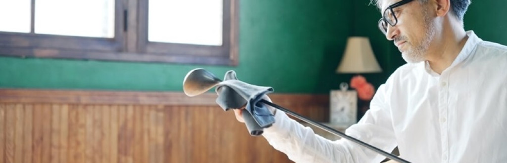 Elderly Asian man polishing a golf club in the room