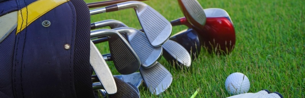 Set of golf clubs over green field