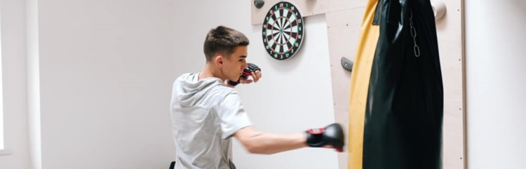 Boy workout with boxing bag in home gym room