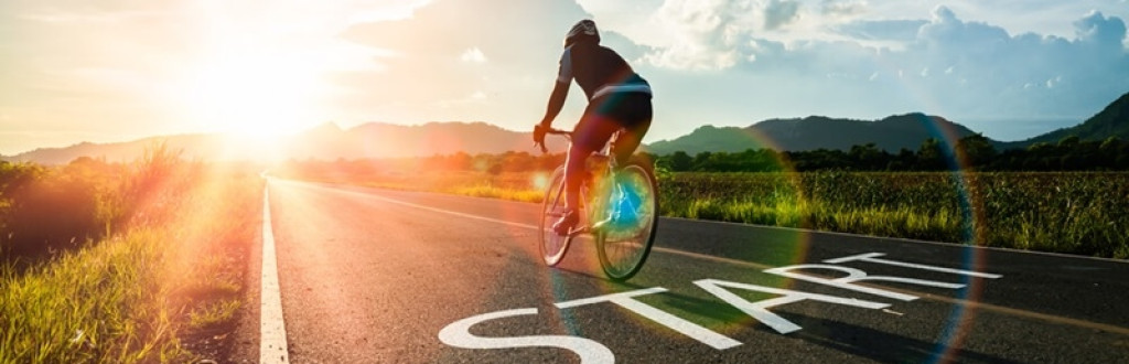 Blurry Man ride on bike and word start written on the road 