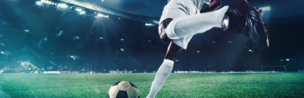 player kicking soccer ball in ground at night time with light on