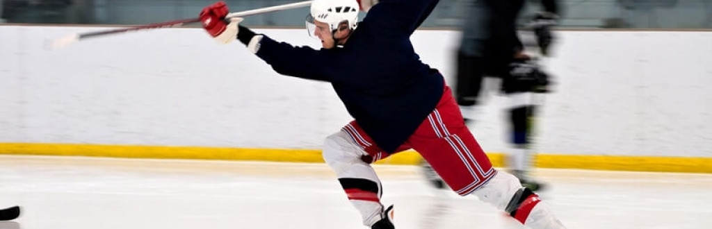 A hockey player shooting the puck as he speeds down the ice