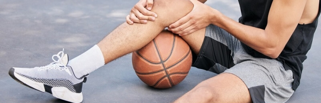 Basketball player sitting holding his injured knee